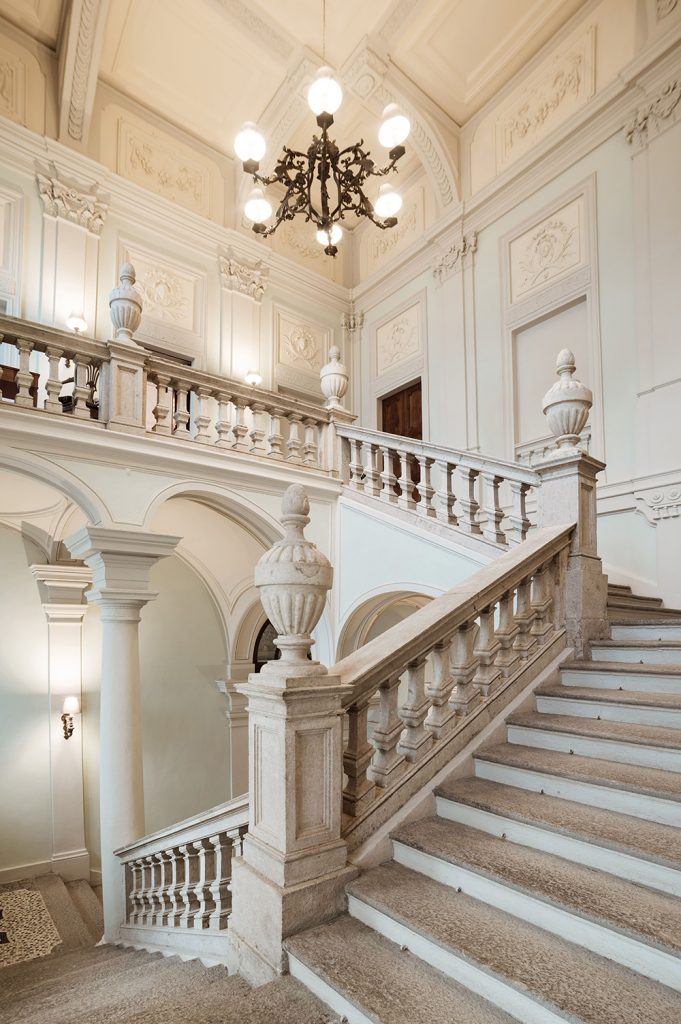 escalier monumental menant à l'étage principal du palais royal, avec rampe en marbre et éclairé par le grand lustre en fer forgé d'origine