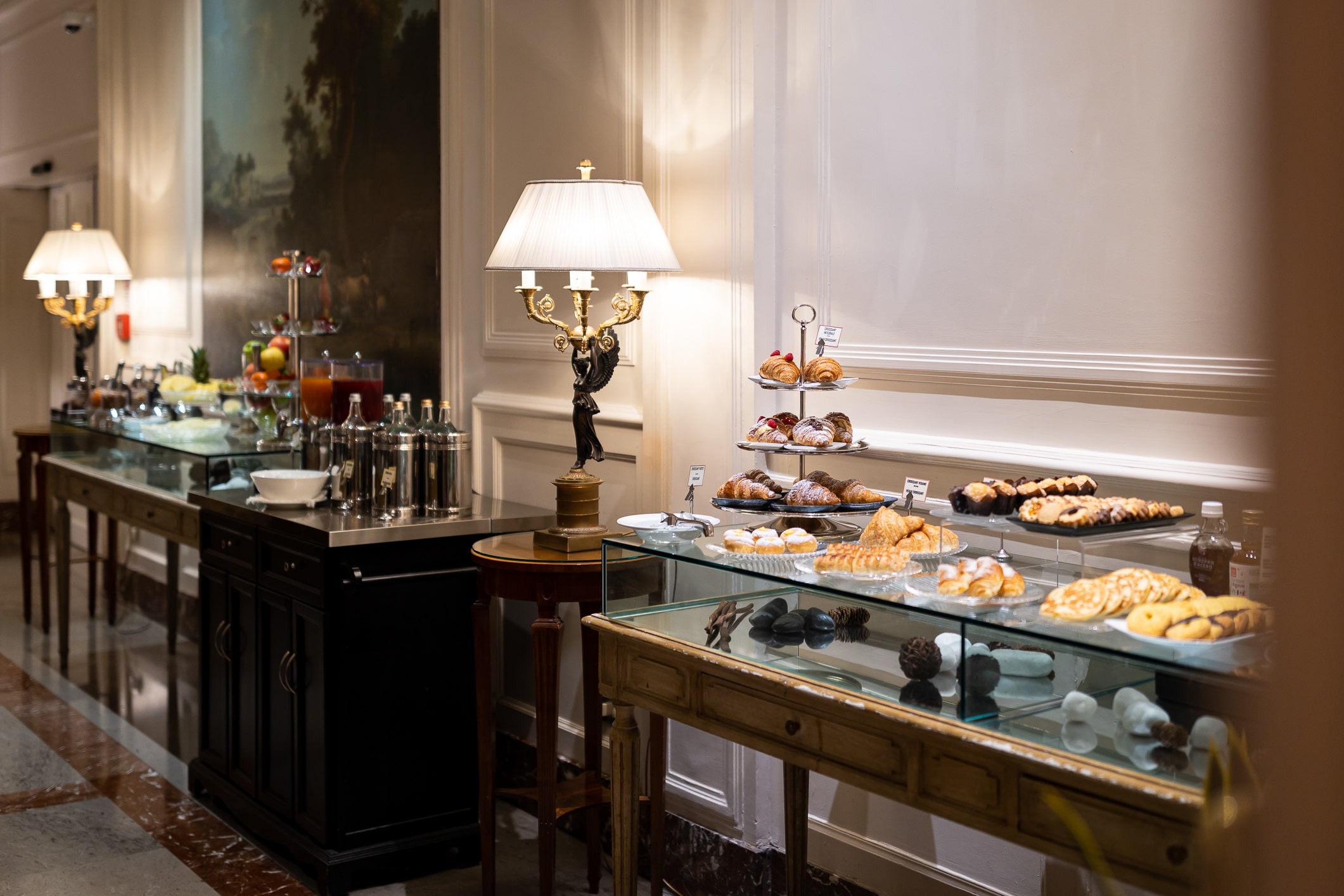 vue sur les deux comptoirs du buffet de petit-déjeuner comprenant du granola, des fruits frais, des jus de fruits et des pâtisseries fraîches avec des croissants, des muffins, des beignets et d'autres pâtisseries.